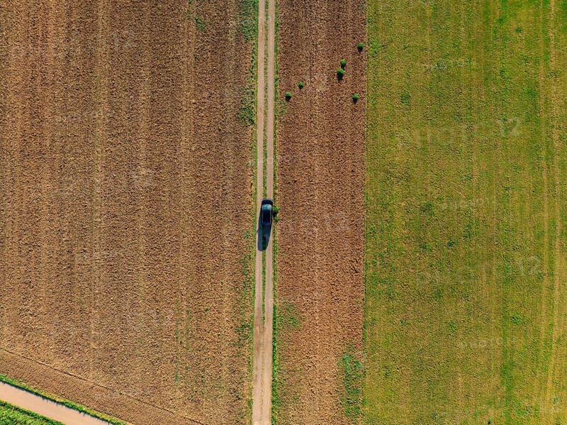 Aerial view of a car on a rural road between fields painted in green and brown colours, car sharing, VW ID5, Calw, Black Forest, Germany, Europe