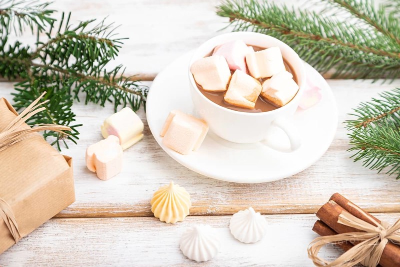 Christmas or New Year composition. Decorations, box, balls, cinnamon, fir and spruce branches, cup of coffee, on a white wooden background. Side view, copy space, selective focus