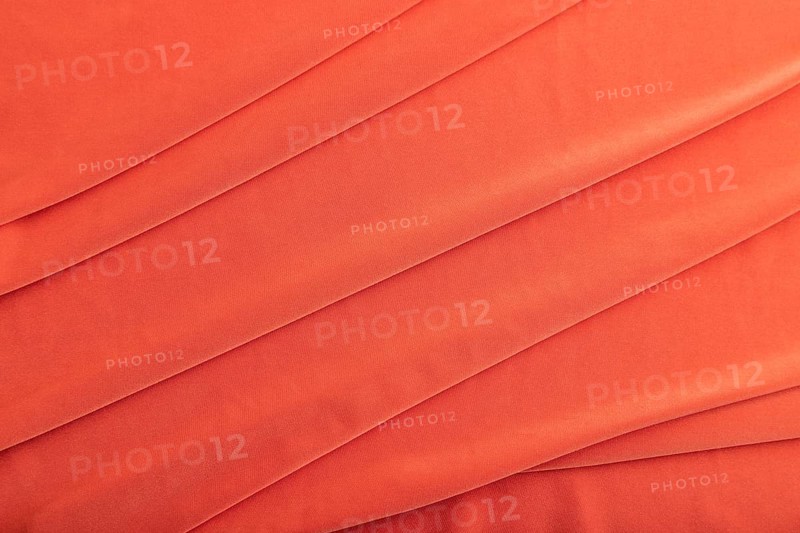 Fragment of red silk tissue. Top view, natural textile background and texture. wave concept, abstract