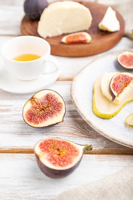 Summer appetizer with pear, cottage cheese, figs and honey on a white wooden background and linen textile. Side view, close up, selective focus