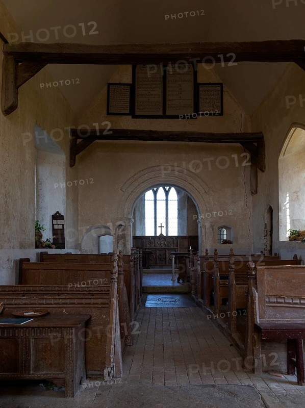 Norman chancel arch and wooden pews inside church of Saint John the Baptist, Wantisden, Suffolk, England, UK