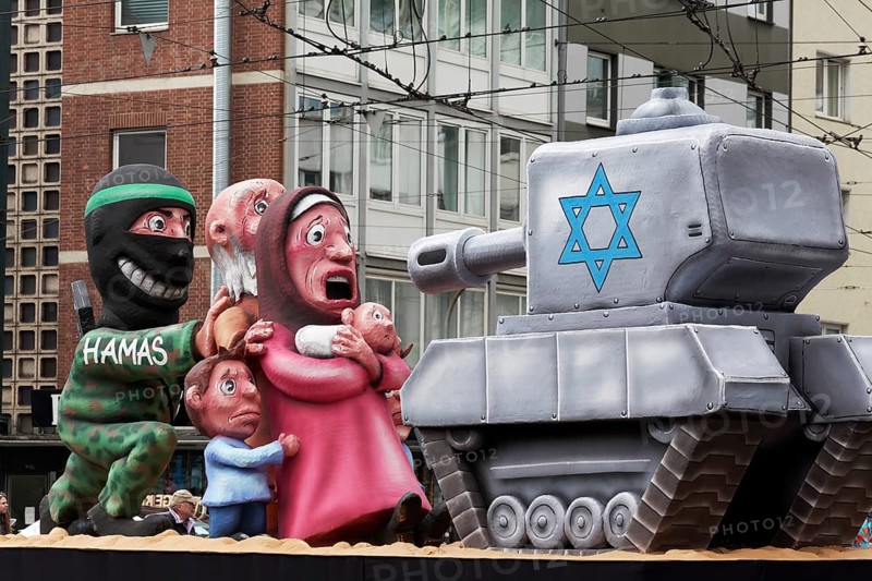 Hamas terrorist hides behind civilians in front of an Israeli tank, papier-mâché figures, satirical float by Jacques Tilly, Rose Monday parade Düsseldorf, North Rhine-Westphalia, Germany, Europe