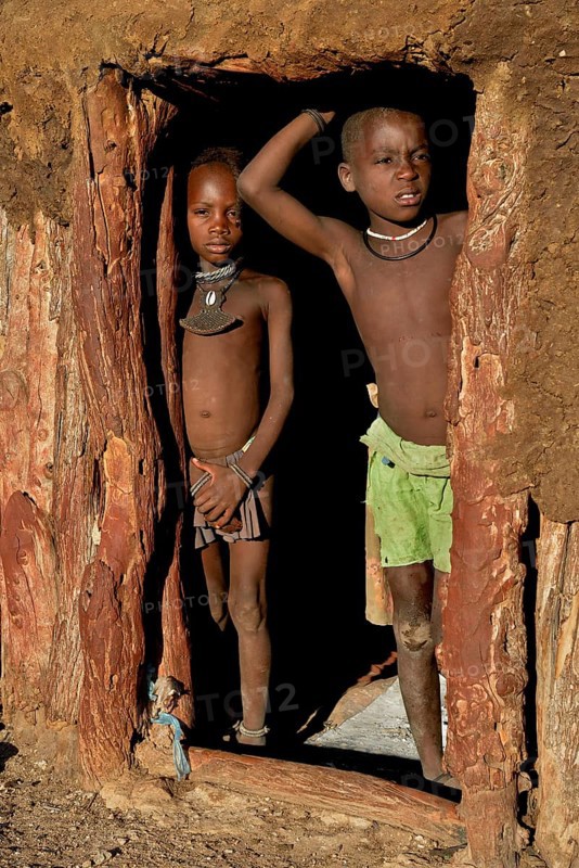 Himba children standing at the door of their hut, Omohanja, Kaokoland, Kunene, Namibia, Africa
