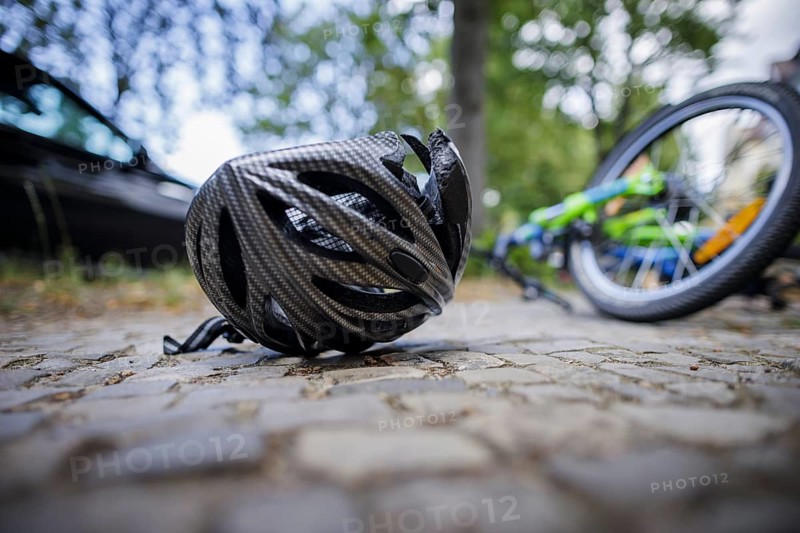Symbol photo on the subject of bicycle accidents (posed scene) . A broken bicycle helmet lies next to a bicycle on a road Berlin, 21/08/2024
