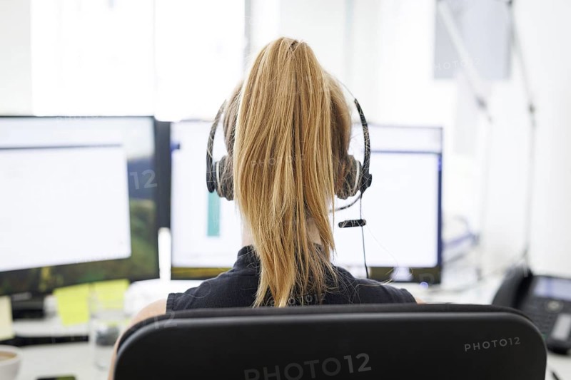 A woman wears headphones in an office in Berlin, 08.08.2024. Working in a call centre