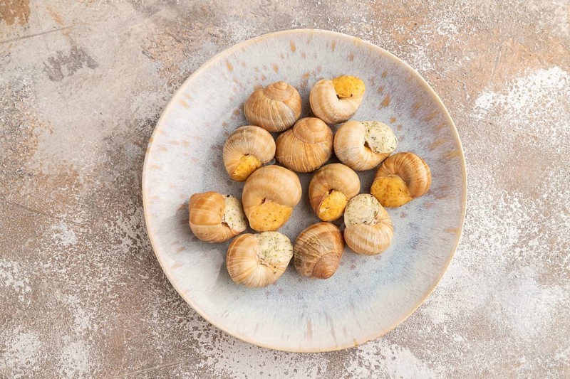 Grape (Burgundy) snails with butter and cheese on brown concrete background. Top view, flat lay