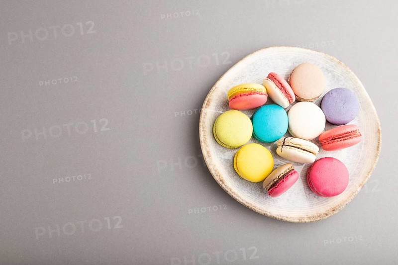 Multicolored macaroons on ceramic plate on gray pastel background. top view, copy space, still life, flat lay. Breakfast, morning, concept