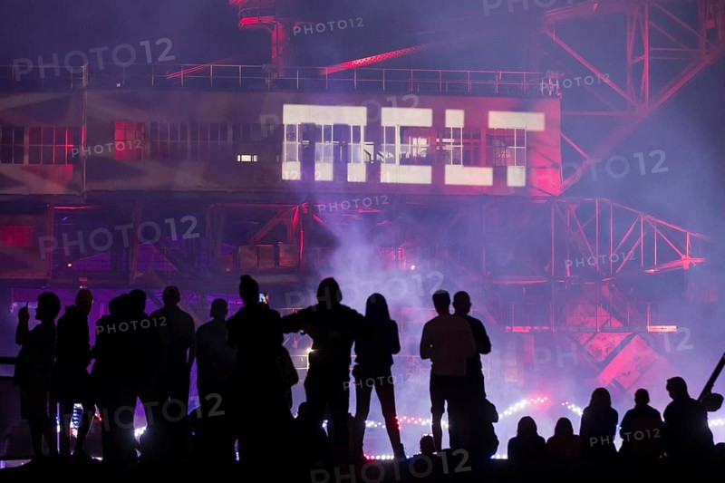 A silhouette of several festival visitors in front of the logo projected onto an excavator at the Melt Festival in Ferropolis on 13 July 2024. After a total of 27 years, the festival will take place for the last time in 2024