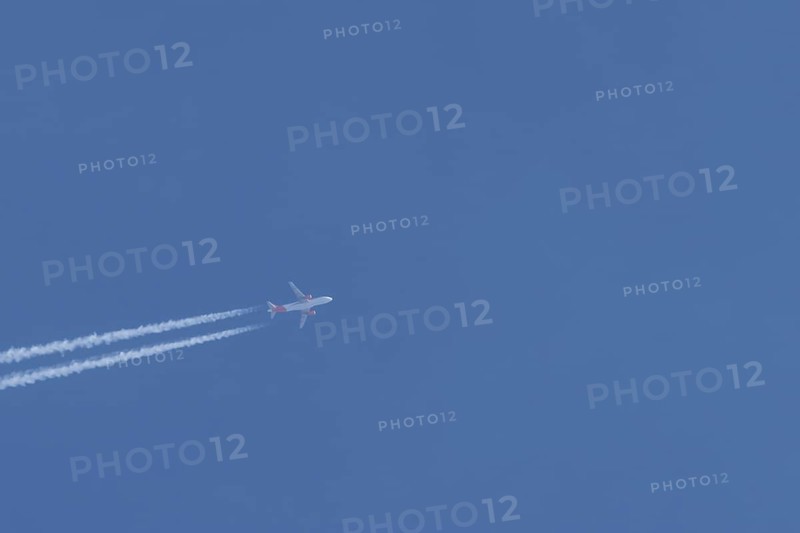 Airbus A320 aircraft of Easyjet airlines in flight with a contrail or vapour trail across a blue sky, England, United Kingdom, Europe