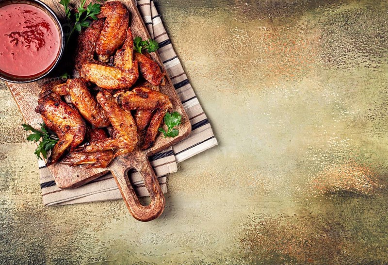 Fried in the oven, chicken wings, with spices, tomato sauce, on a cutting board, gray background, no people, homemade