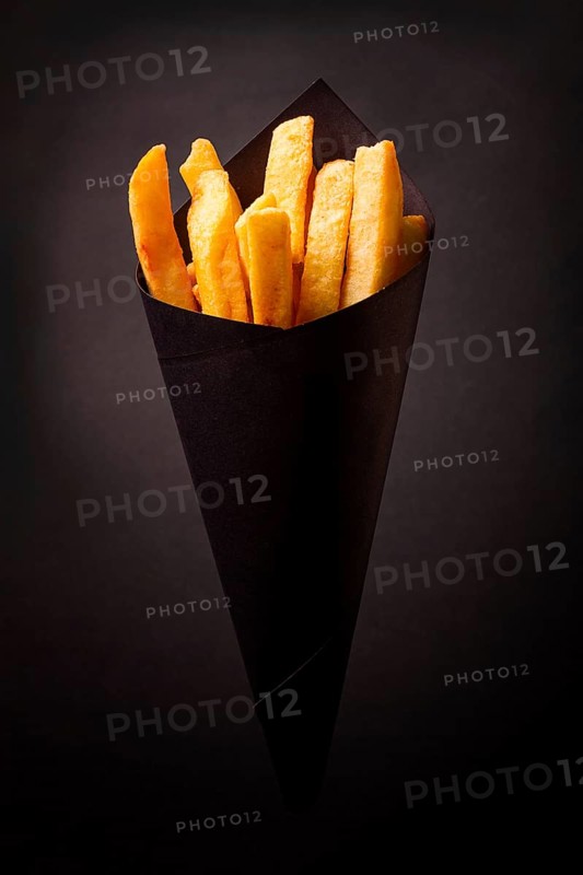 French fries, in black paper packaging, on a black background, close-up, selective focus