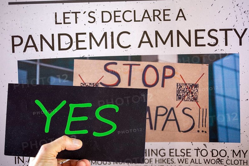 Symbolic image of Pandemic Amnesty: a section of a symbolic newspaper with a sign reading YES held in front of it. In the USA and many other countries, a debate has begun on coming to terms with the corona measures