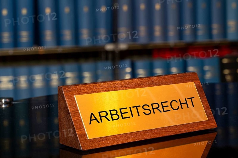 Symbolic image of labour law: Brass sign with the inscription Labour law in front of a large bookshelf (Composing)