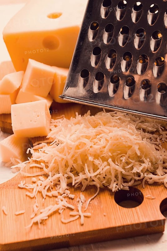 Grated cheese, Maasdam, on a cutting board, grater and cheese knife, close-up, no people