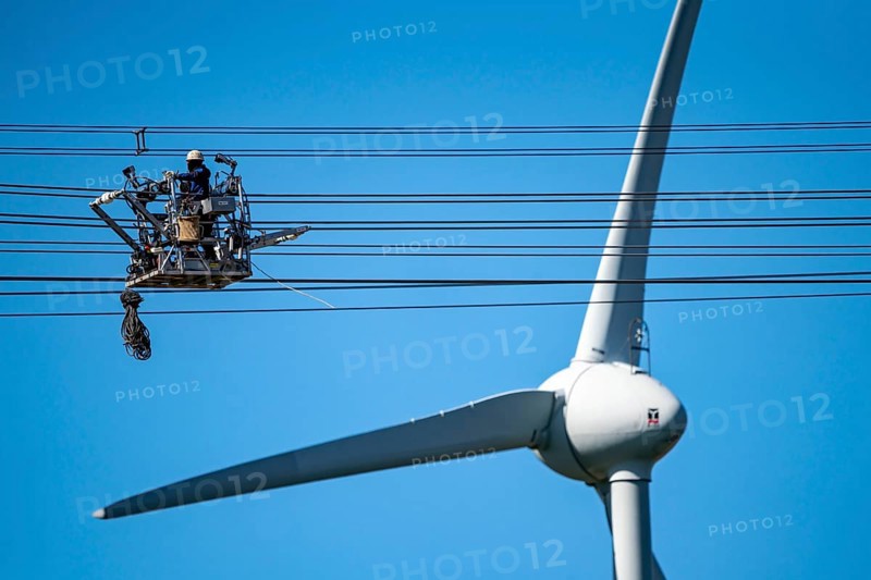 Construction of a new line route, 380 KV extra-high voltage line between Osterath and Gohr, near Neuss, fitters in cable trolleys, on the conductor cables, installing field spacers at great heights, wind power station, North Rhine-Westphalia, Germany, Europe