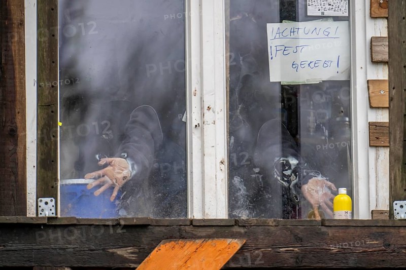 2nd day of the clearing of the hamlet Lützerath, by the police, of tree houses and huts, activist has taped herself to the glass pane of a window, from the inside, at the opencast lignite mine Garzweiler 2, Erkelenz, North Rhine-Westphalia, Germany, Europe