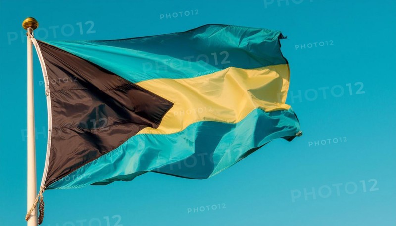 The flag of the Bahamas flutters in the wind, isolated against a blue sky