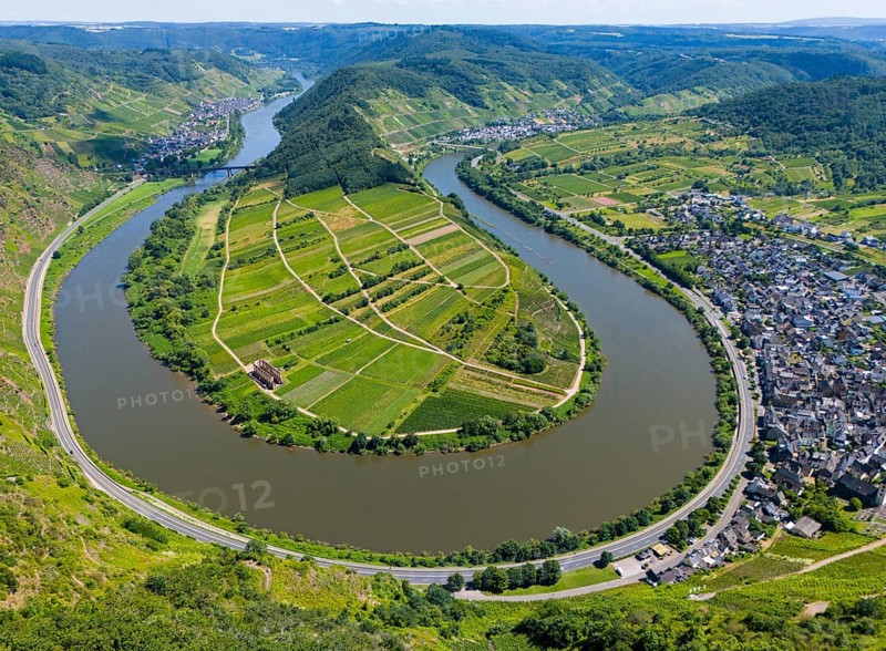 A winding river bend surrounds an agricultural landscape surrounded by hills, with a neighbouring village and vineyards, aerial view, Moselle, Moselle bend, Bremm, Cochem, Cochem-Zell, Rhineland-Palatinate, Germany, Europe