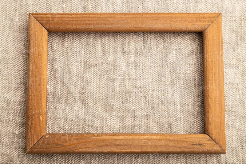 Wooden frame on smooth white linen tissue. Top view, flat lay, natural textile background and texture