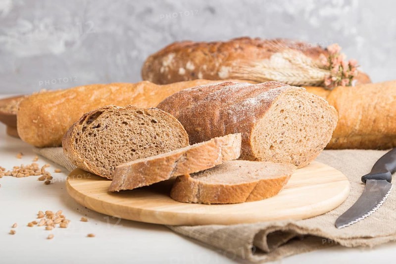 Sliced bread with different kinds of fresh baked bread on a white wooden background. side view, close up, selective focus