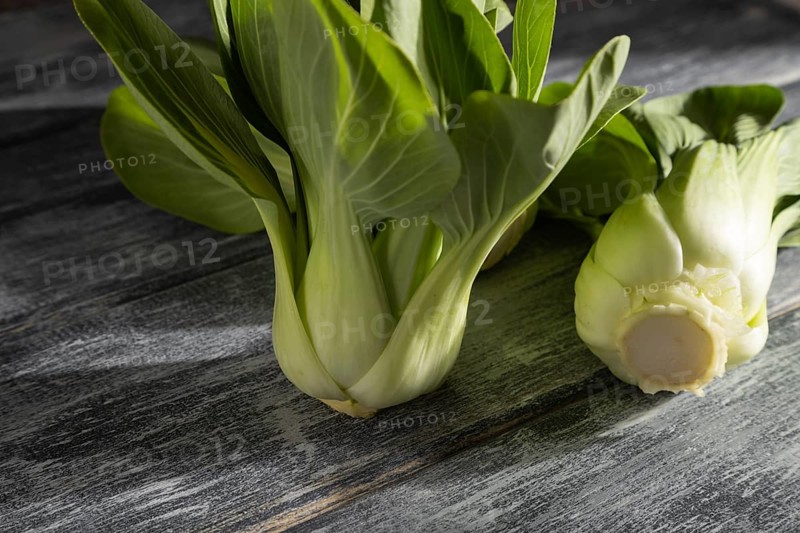 Fresh green bok choy or pac choi chinese cabbage on a gray wooden background. Hard light, contrast. Side view, close up