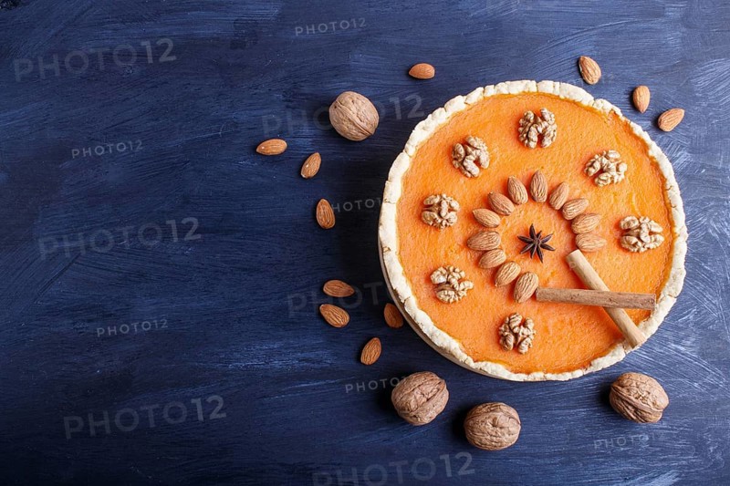 Traditional american sweet pumpkin pie decorated with nuts, on dark blue wooden background. top view, copy space