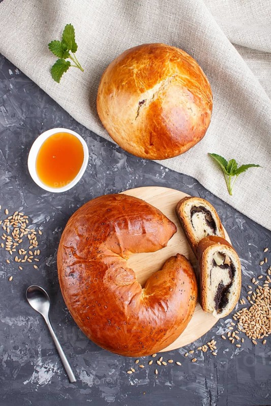 Homemade yeast buns and rolls with poppy seeds and honey on a black concrete background. top view, flat lay