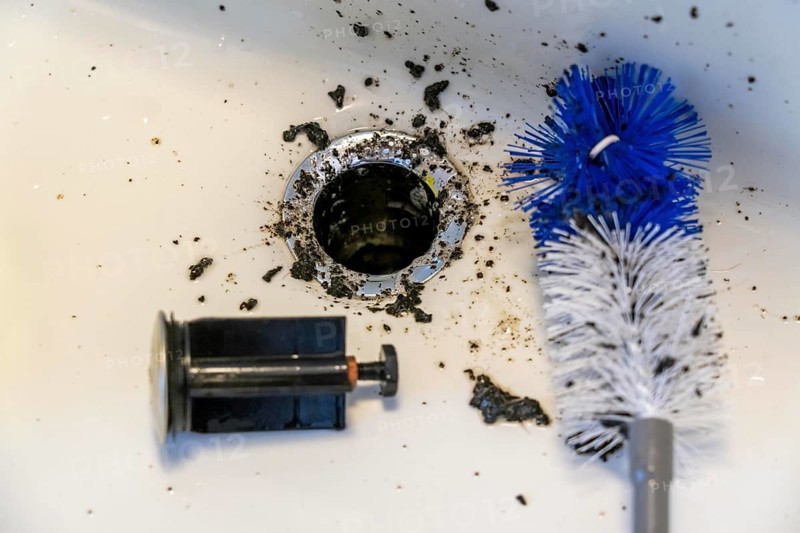 Cleaning a sink, hand basin, bathroom, with the help of a longer brush, the dirt, deposits, mould accumulated over time are removed, housework, cleaning work