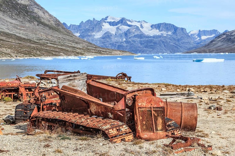 Rusty cars and barrels on a fjord in front of steep mountains, remains of a US airbase from the Second World War, Ikateq Fjord, East Greenland, Greenland, North America