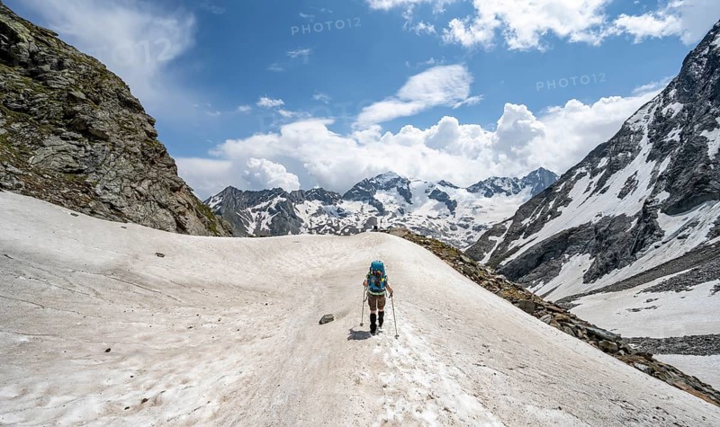 Mountaineer hiking in a snowfield, Nördliche Mörchnerscharte, behind mountain peak Greizer Spitze with snow, Berliner Höhenweg, Zillertal Alps, Tyrol, Austria, Europe