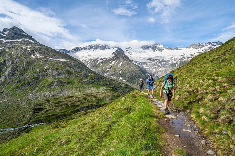 Three mountaineers on a hiking trail in a picturesque mountain landscape, mountain peak with snow and glacier Hornkees and Waxeggkees, summit Hornspitzen and Großer Möseler, Berliner Höhenweg, Zillertal Alps, Tyrol, Austria, Europe