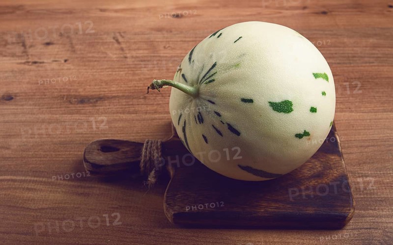 Dino melon, white with green stripes, small size, on the table, close-up, no people