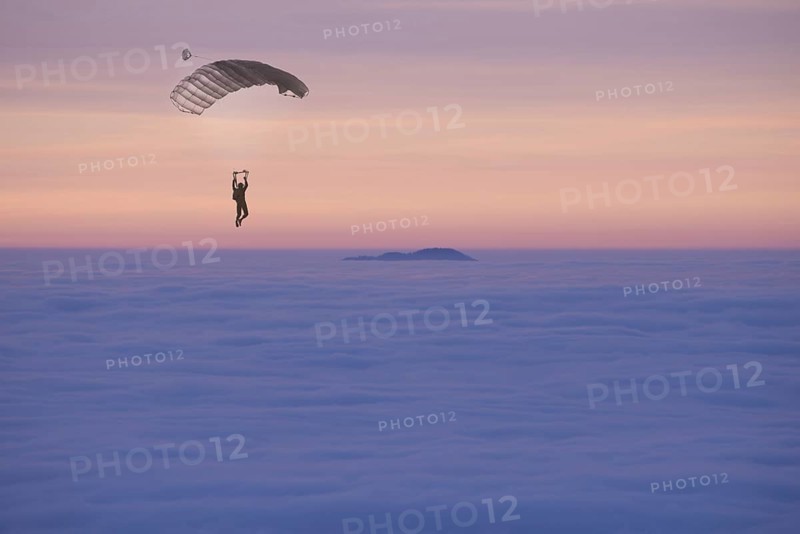 Paraglider Flying over a Cloudscape with a Mountain Peak in Sunset in Ticino, Switzerland, Europe