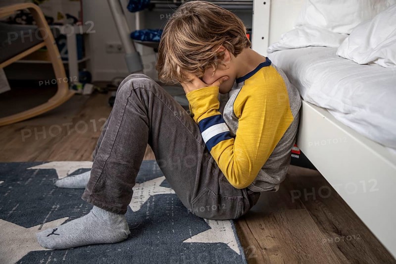 Kind mit Kopfschmerzen, Junge 9 Jahre alt, mit schmerzverzerrtem Gesicht, symbolisches Bild