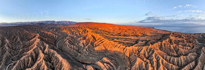 Panorama, landscape of eroded hills at Lake Issyk Kul, badlands at sunrise, mountain peaks of the Tien Shan Mountains in the background, aerial view, Canyon of the Forgotten Rivers, Issyk Kul, Kyrgyzstan, Asia