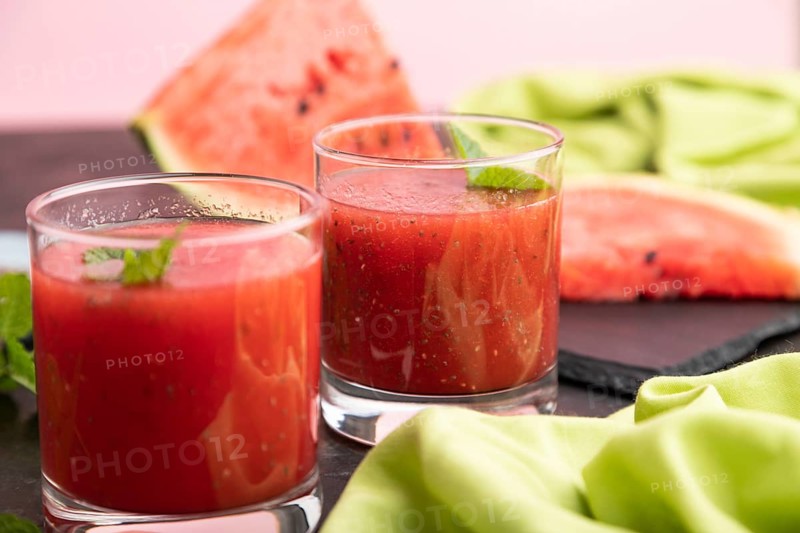 Watermelon juice with chia seeds and mint in glass on a black concrete background with green textile. Healthy drink concept. Side view, close up, selective focus