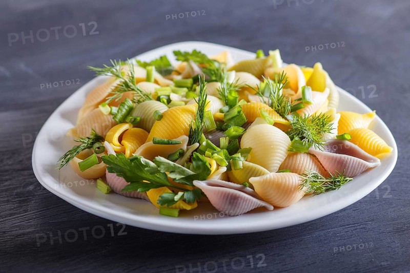 Conchiglie colored pasta with fresh greengrocery on black wooden background. close up, selective focus