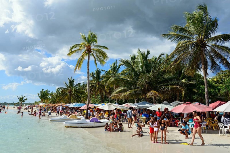 Beachgoers relax under colourful umbrellas next to the calm sea, Boca Chica, Santo Domingo Province, Dominican Republic, Hispaniola, Caribbean, America, Central America
