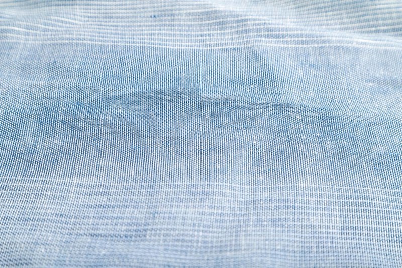 Fragment of smooth blue linen tissue. Side view, natural textile background and texture