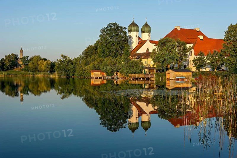 Romanesque Benedictine abbey Seeon monastery, monastery church St. Lambert with reflection in the monastery lake, calm smooth water in the evening light at sunset, behind the side church Maria zu Breuhausen, also Bräuhausen, Seeon-Seebruck, Chiemgau, Upper Bavaria, Bavaria, Germany, Europe