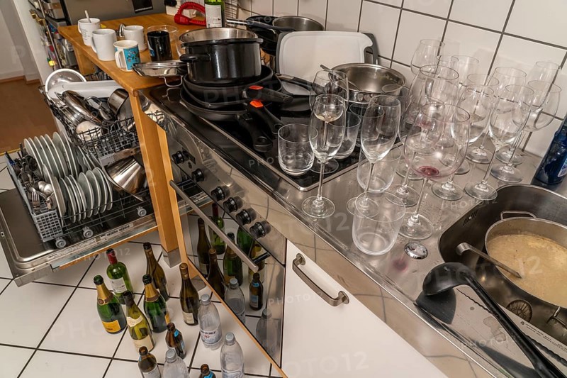 Kitchen after a big dinner, cooking party, dishwasher, full, with cleaned dishes, dirty glasses, pots, cooking utensils on the sink, waiting to be washed