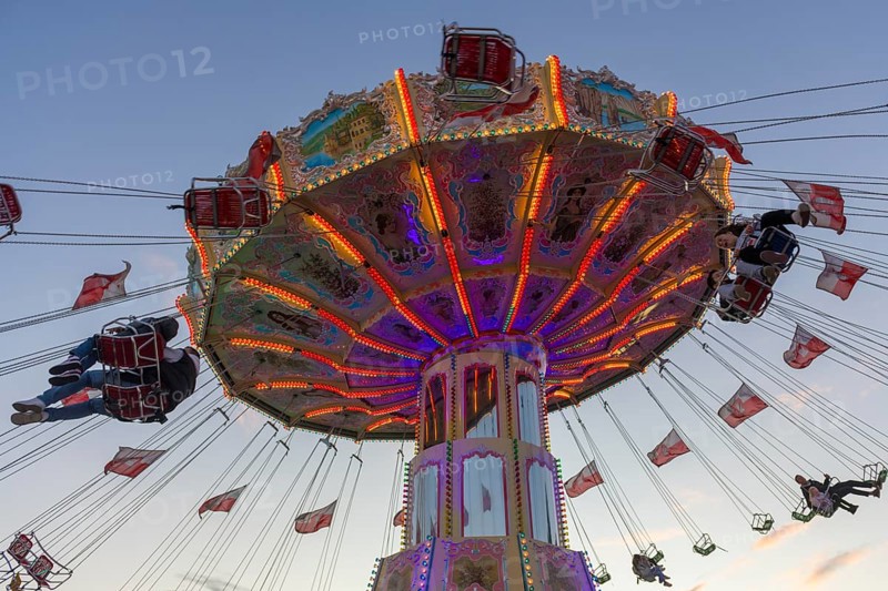 A colourfully illuminated carousel with swinging seats against an evening sky, wave flight, chain carousel, Bad Cannstatt, Stuttgart, Baden-Württemberg, Germany, Europe