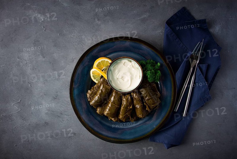 Dolma, cabbage rolls, grape leaves with filling, white sauce, lemon and herbs, rustic, selective focus, no people