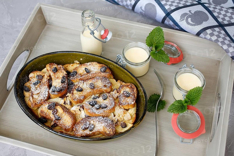 Swabian cuisine, Ofenschlupfer, sweet main course or dessert, dessert, sweet dish, typical Swabian, classic, from the oven, casserole, leftovers, rolls with sultanas, apples, gratinated, vanilla sauce, icing sugar, served on a tray, home cooking, traditional cuisine, food photography, studio, Germany, Europe