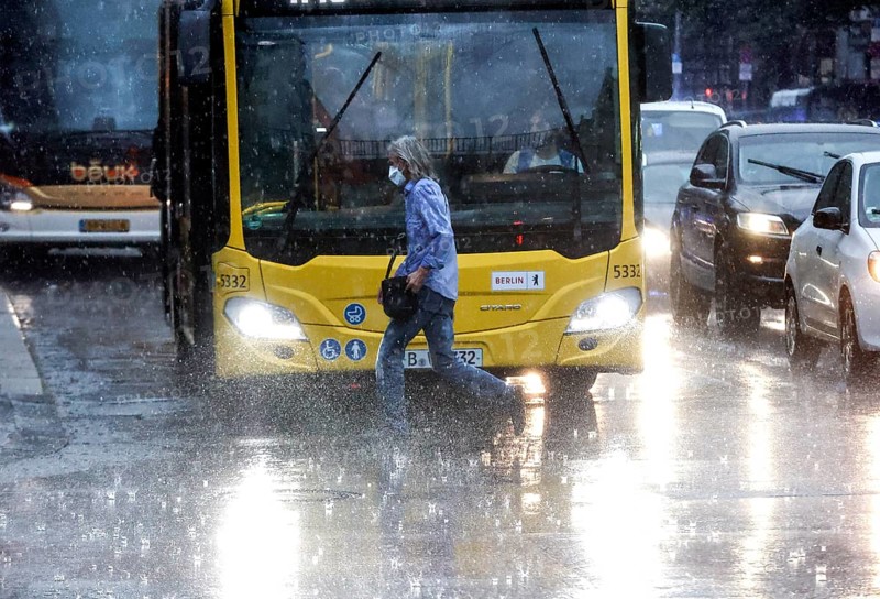 People run across Potsdamer Strasse in heavy rain. After weeks of heat, the first heavy rain brought cooling, Berlin, 15.08.2022