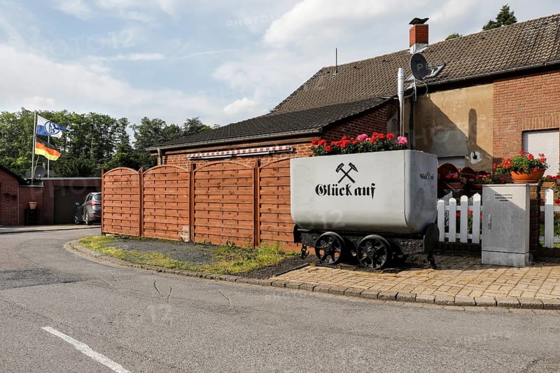 A coal lorry with the miner's greeting Glück auf stands in front of a house in a housing estate in Gelsenkirchen. The Schalke 04 flag and a German flag flutter in the background, Gelsenkirchen, 11/06/2021