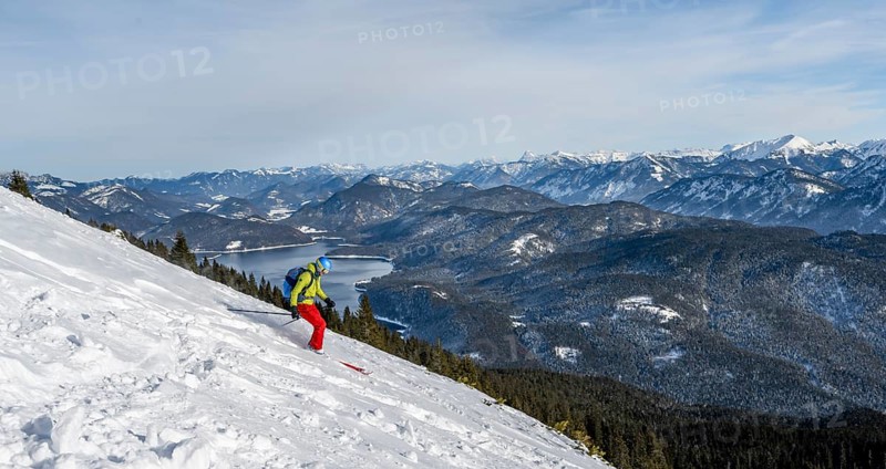 Skiers skiing down the Simetsberg, view of Walchensee and mountain panorama, Estergebirge, Bavarian Prealps, Bavaria Germany