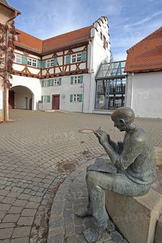 Historical town library with stepped gable and fountain with sculpture newspaper reader, Pfleghof, bronze sculpture newspaper, book reader, reader, book, reading, literature, head, figure, book, holding, hand, Langenau, Alb-Donau-Kreis, Schwäbische Alb, Baden-Württemberg, Germany, Europe