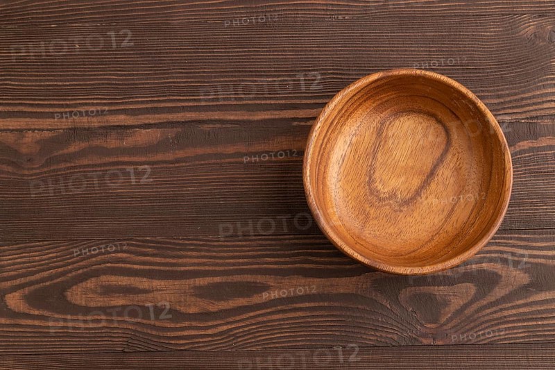 Empty brown wooden bowl on brown wooden background. Top view, copy space, flat lay