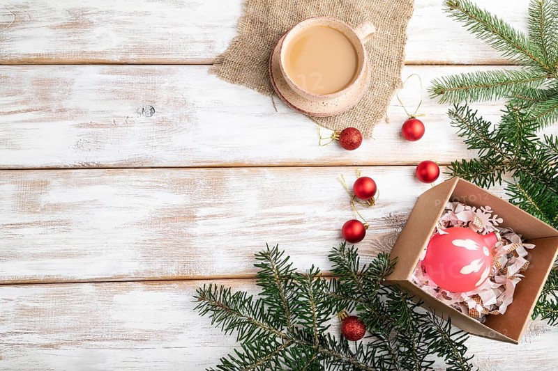 Christmas or New Year composition. Decorations, red balls, fir and spruce branches, cup of coffee on a white wooden background. Top view, flat lay, copy space